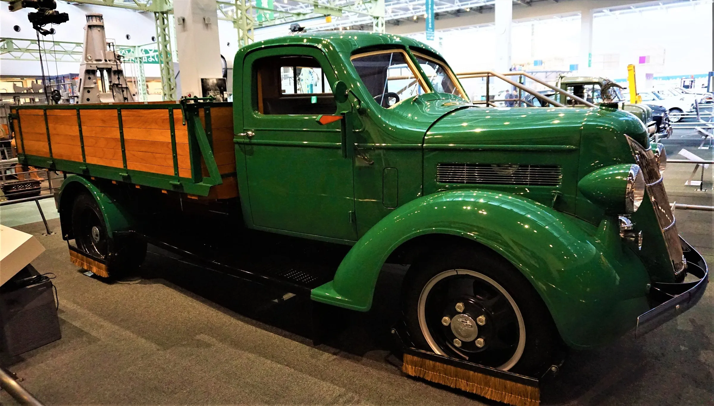 A restored green 1935 Toyoda G1 truck with a wooden cargo bed, on display at the Toyota Commemorative Museum of Industry and Technology.